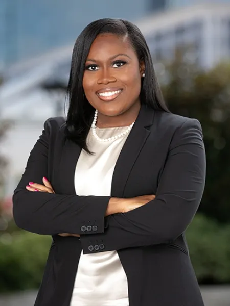 Woman with straight black hair, her arms folded wearing a black blazer 